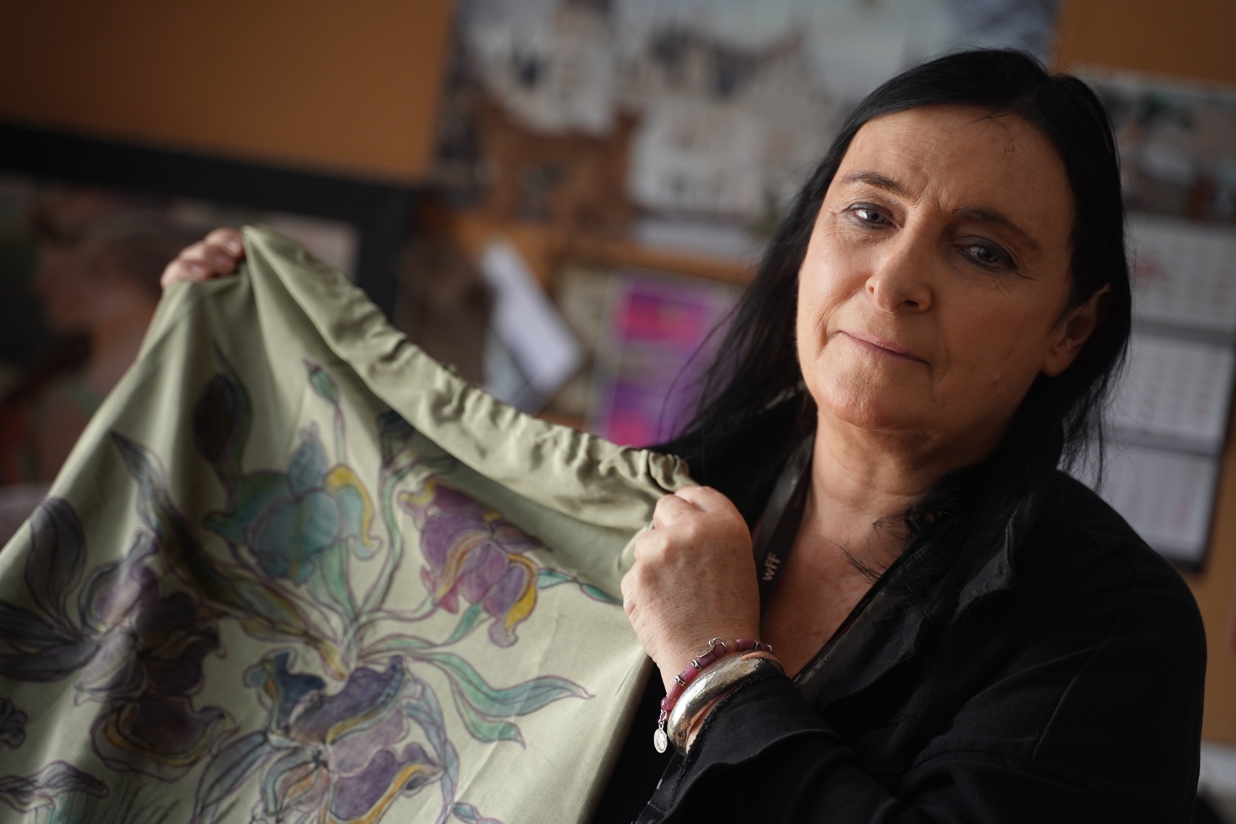 Maria Duffek w pracowni trzyma zieloną malowaną tkaninę